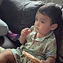 toddler, child, pajamas, snack, rice_cake, couch, leather, indoor, window, plants, home, relaxed, sitting, cute, face, person, food, leisure, comfort, young_child