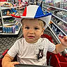 aisle, boy, child, clothing, colorful, cowboy_hat, curious, cute, face, floor, indoor, person, products, retail, shelf, shopping, shopping_cart, store, toddler, white_tshirt