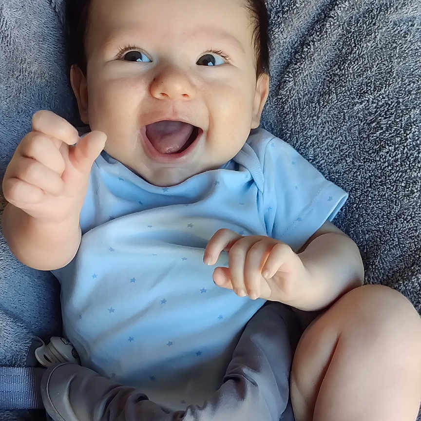 éric participe au concours pour gagner de l'argent avec cette photo : baby, blue_clothing, bright_eyes, casual, child, chubby_legs, comfort, cute, hand_gesture, happy, indoors, infant, joyful, playful, plush_seat, portrait, seated, smiling, soft_texture, young