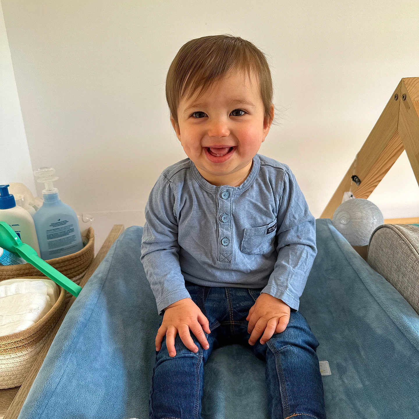 Liam a rejoint le concours — aidez-le/la à gagner de superbes lots ! baby, baby_products, blue_shirt, changing_pad, child, clothing, cute, denim_jeans, happy, indoor, infant, nursery, person, seated, smile, smiling, soft_texture, toddler, white_socks, wooden_frame