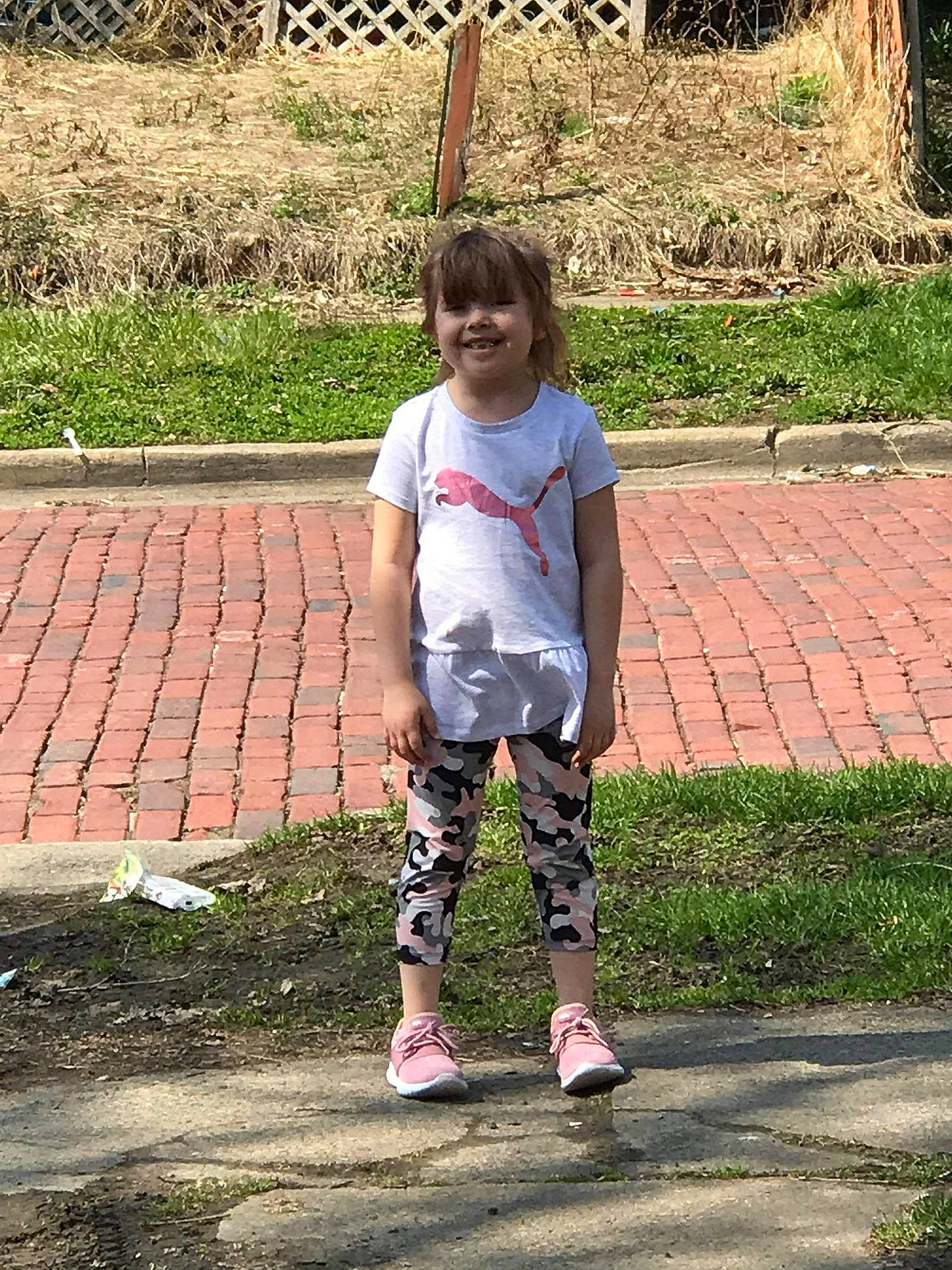 Kennaleigha is registered to the contest to win money with this photo: asphalt, face, footwear, grass, hair, happy, head, joy, knee, leisure, pattern, people_in_nature, person, plant, recreation, sidewalk, sleeve, smile, t_shirt, thigh