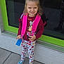 child, girl, backpack, smile, sidewalk, window, reflection, floral_leggings, sneakers, casual_clothing, outdoor, daylight, happy, cute, standing, concrete, urban, playful, young, portrait