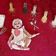 Ayla participe au concours pour gagner de l'argent avec cette photo : baby, blanket, chef_costume, cooking, cute, food, fork, grains, headwear, indoors, infant, kitchen_tools, laying_down, playful, red_blanket, rolling_pin, smiling, spoon, whisk, white_clothing