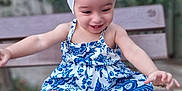 Ayla participe au concours pour gagner de l'argent avec cette photo : barefoot, bench, blue, bow, child, cute, dress, garden, happy, headband, nature, outdoor, pattern, person, playful, sitting, smiling, toddler, wood, young