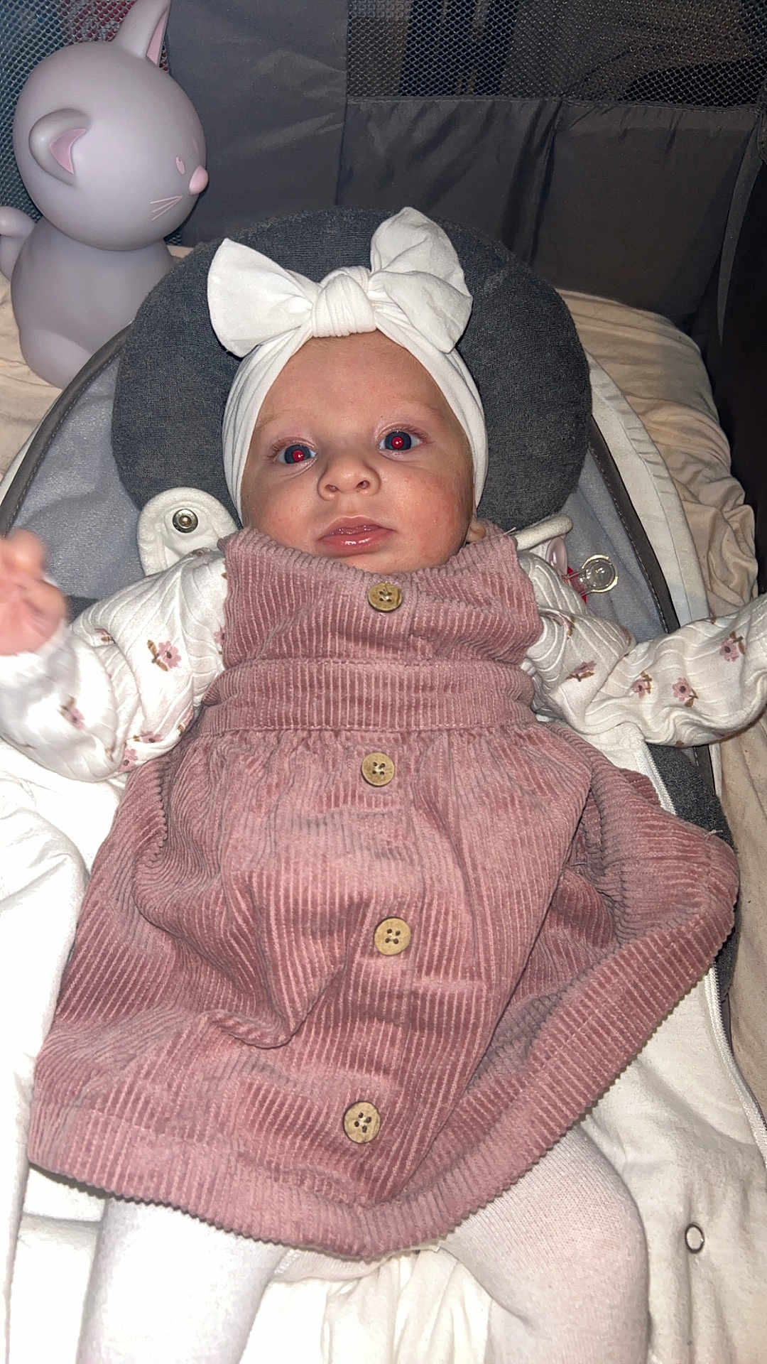 Inäya a rejoint le concours — aidez-le/la à gagner de superbes lots ! baby, infant, pink_dress, headband, bow, cushion, cat_lamp, red_eye, white_tights, baby_seat, indoor, close_up, child, cute, soft_lighting, portrait, clothing, sleeping_area, toy, resting