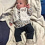 baby, infant, blanket, clothing, vest, boots, pants, floral_pattern, fur, fabric, person, cute, lying_down, indoor, soft_texture, cozy, small, child, portrait, footwear