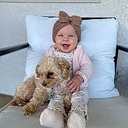 Evelina is registered to the contest to win money with this photo: baby, child, dog, pet, cushion, chair, knitted_headband, smile, happy, cozy, indoor, clothing, socks, fur, small_dog, portrait, cute, comfort, window, hand