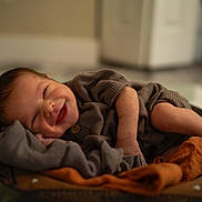 Idris is registered to the contest to win money with this photo: baby, smiling, sleeping, cozy, blanket, bowl, infant, cute, happy, clothing, face, skin, hands, feet, indoors, portrait, newborn, soft, warm, resting