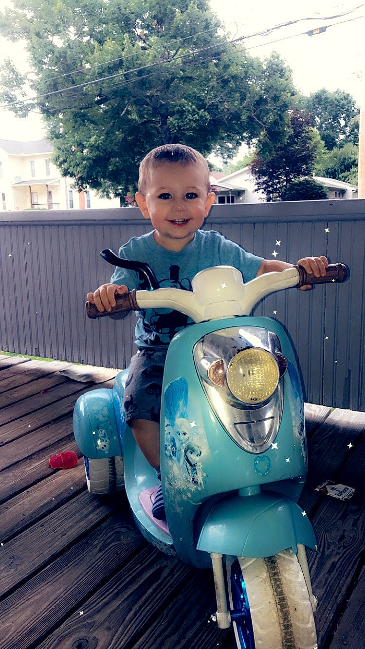 Hayden is registered to the contest to win money with this photo: automotive_design, automotive_lighting, automotive_tire, cool, eye, face, fender, hair, happy, head, joy, motor_vehicle, person, photograph, product, smile, tire, toddler, tree, vehicle