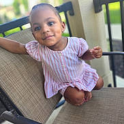 Nashkiely joined the competition — help win amazing prizes! child, toddler, baby, portrait, smiling, seated, dress, striped_clothing, pink, chair, outdoor, patio, furniture, face, eyes, earrings, barefoot, relaxed, candid, photography