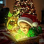 toddler, child, santa_hat, christmas_tree, book, reading, holiday, magic, glowing, grinch, pajamas, blanket, indoors, lighting, smiling, festive, cozy, floor, illustration, winter