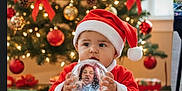 Zaiden joined the competition — help win amazing prizes! baby, child, christmas_tree, christmas_lights, christmas_ornaments, santa_hat, santa_costume, snow_globe, holiday, presents, gift_wrapping, indoors, festive, decorations, red_clothing, cute, smiling, celebration, winter, holiday_spirit