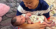 Kingston is registered to the contest to win money with this photo: child, baby, sibling, bed, blanket, pillow, smile, curly_hair, mohawk, newborn, holding, indoor, family, cute, happy, person, portrait, clothing, skin, love