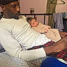Legend is registered to the contest to win money with this photo: man, baby, indoor, bed, clothing, towel, hanger, furniture, person, child, striped_pajamas, relaxing, casual, home, portrait, sleepwear, blanket, seated, resting, curious