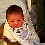 Legend is registered to the contest to win money with this photo: baby, newborn, infant, blanket, hospital, bed, hand, person, wrapped, swaddled, medical_equipment, indoor, skin, face, head, clothing, comfort, care, human, portrait