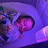 Legend is registered to the contest to win money with this photo: newborn, baby, sleeping, swaddled, blanket, crib, mesh, hand, face, purple_light, infant, cozy, bed, peaceful, resting, child, indoors, soft_light, portrait, cute