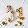 baby, infant, child, flower_arrangement, number_one, blanket, white_background, yellow_flowers, orange_flowers, floral_decoration, celebration, portrait, cute, newborn, laying_down, clothing, soft_texture, milestone, first_birthday, decor