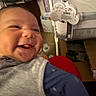 Legend is registered to the contest to win money with this photo: baby, smile, infant, clothing, face, indoor, crib, furniture, happy, person, child, babywear, candid, room, toy, baby_bed, expression, cute, warm, cozy