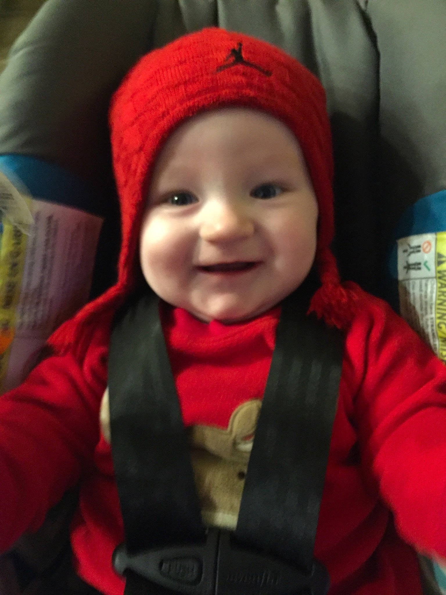 Kaiden is registered to the contest to win money with this photo: baby, baby_carriage, baby_products, beanie, cap, car_seat, cheek, child, headgear, joy, knit_cap, knitting, person, product, red, smile, toddler, wool
