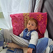 Nolan participe au concours pour gagner de l'argent avec cette photo : toddler, child, chair, blanket, towel, sock, clothing, indoor, person, face, curious, sitting, plastic_chair, patterned_sock, pillow, casual_wear, young_child, relaxed, home, comfort