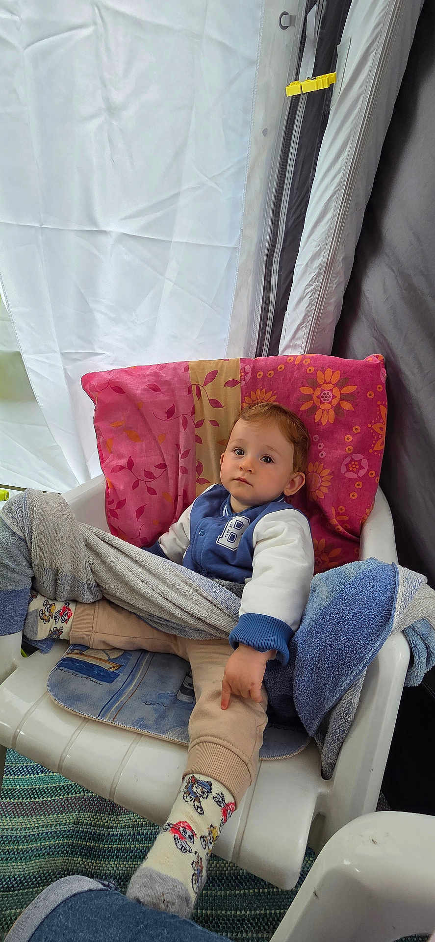 Nolan participe au concours pour gagner de l'argent avec cette photo : toddler, child, chair, blanket, towel, sock, clothing, indoor, person, face, curious, sitting, plastic_chair, patterned_sock, pillow, casual_wear, young_child, relaxed, home, comfort