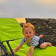 Nolan participe au concours pour gagner de l'argent avec cette photo : baby, beach, child, green_chair, happy, lounge_chair, nature, outdoor, playful, portrait, sand, sea, shorts, smiling, stone_wall, striped_shirt, sunlight, sunset, toddler, vacation