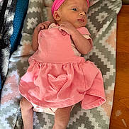 Xylah is registered to the contest to win money with this photo: baby, infant, pink_dress, headband, blanket, patterned_blanket, newborn, cute, lying_down, indoors, wooden_surface, small_hands, small_feet, soft_fabric, heart_patch, clothing, baby_girl, resting, portrait, skin