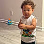 Damián is registered to the contest to win money with this photo: toddler, child, curly_hair, indoor, wooden_floor, sleeveless_shirt, train_graphic, pants, adidas, standing, hands_clasped, wall, power_outlet, toy, flooring, young_child, casual_clothing, person, cute, curious
