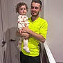 Priscilla is registered to the contest to win money with this photo: child, toddler, man, indoor, hallway, door, curly_hair, pajamas, butterfly_pattern, smile, holding, person, clothing, neon_shirt, shorts, white_wall, carpet, family, happy, portrait