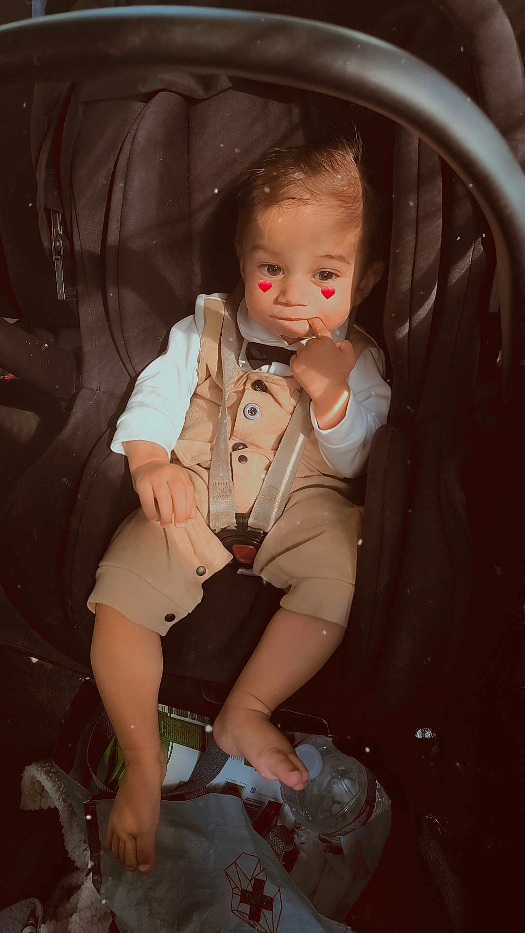 Malone Audet a rejoint le concours — aidez-le/la à gagner de superbes lots ! toddler, car_seat, child, overalls, white_shirt, bow_tie, car_interior, water_bottle, bag, foot, hand, face, cute, sitting, indoor, seatbelt, expression, heart_emoji, clothing, baby