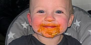Nolan is registered to the contest to win money with this photo: baby, child, messy_face, high_chair, food, orange_food, smile, blue_eyes, short_hair, black_clothing, elephant_print, hand, indoor, kitchen, feeding, cute, happy, toddler, face, messy