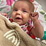Evie is registered to the contest to win money with this photo: baby, infant, smiling, towel, blanket, floral_pattern, crib, happy, cute, child, person, portrait, lying_down, indoors, closeup, skin, face, hand, fabric, cozy