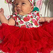 Evie joined the competition — help win amazing prizes! baby, infant, tutu, headband, strawberry, red_skirt, floral_blanket, cute, smiling, lying_down, socks, clothing, patterned_outfit, pink, white, soft_texture, indoors, face, person, child