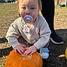 baby, child, toddler, pacifier, pumpkin, autumn, outdoor, portrait, face, blue_eyes, blonde_hair, sweater, shoes, sitting, hands, garden, grass, playground, adult_legs, daylight