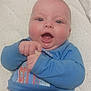 Konrad participe au concours pour gagner de l'argent avec cette photo : baby, infant, smiling, blue_shirt, striped_pants, hand, face, eyes, mouth, mattress, white_background, lying_down, child, cute, happy, skin, person, indoors, expression, joy