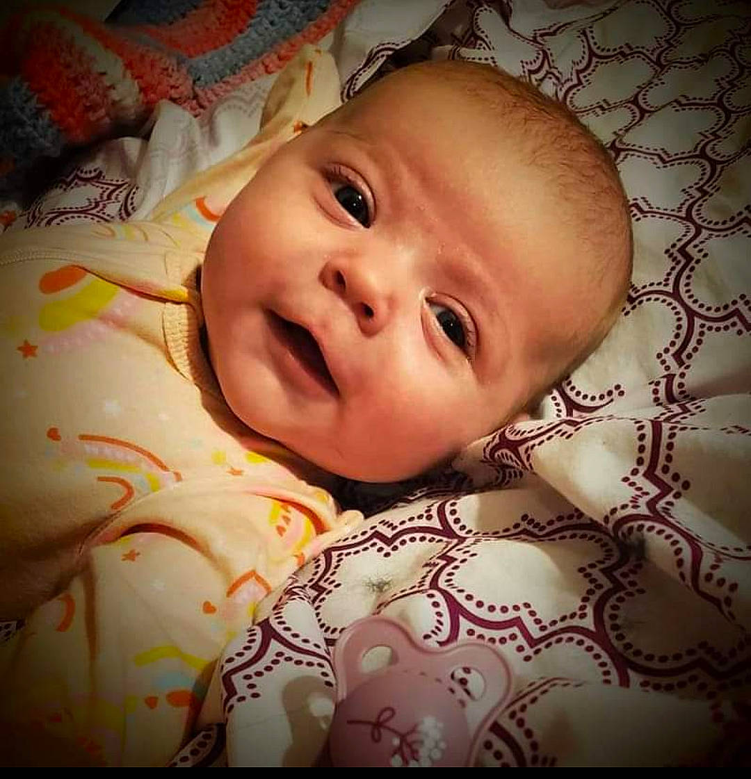 Kenzie is registered to the contest to win money with this photo: baby, baby_products, baby_toddler_clothing, bedtime, cheek, child, comfort, eyelash, happy, human_body, linens, lip, nose, pattern, person, portrait_photography, room, skin, smile, textile