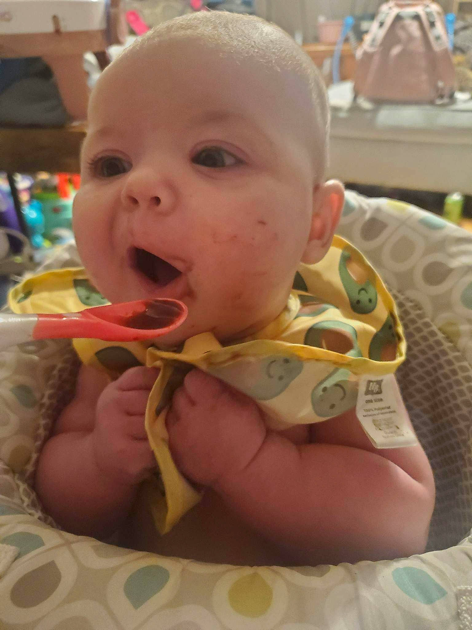 Kenzie is registered to the contest to win money with this photo: baby, baby_toddler_clothing, bib, biting, cheek, child, chin, comfort, eye, eyelash, fun, happy, head, iris, mouth, nose, person, room, sitting, skin