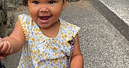 Harmonii is registered to the contest to win money with this photo: child, toddler, baby, smiling, happy, portrait, outdoors, garden, sidewalk, steps, stone_wall, rocks, greenery, bow, headband, curly_hair, floral_outfit, sandal, pacifier, standing