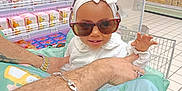 Elyssa participe au concours pour gagner de l'argent avec cette photo : baby, child, sunglasses, headband, adult_hand, grocery_store, shopping_cart, aisle, shelf, products, tattoo, bracelet, white_clothing, floor_tiles, shopping, retail, cute, fashion, smile, indoor