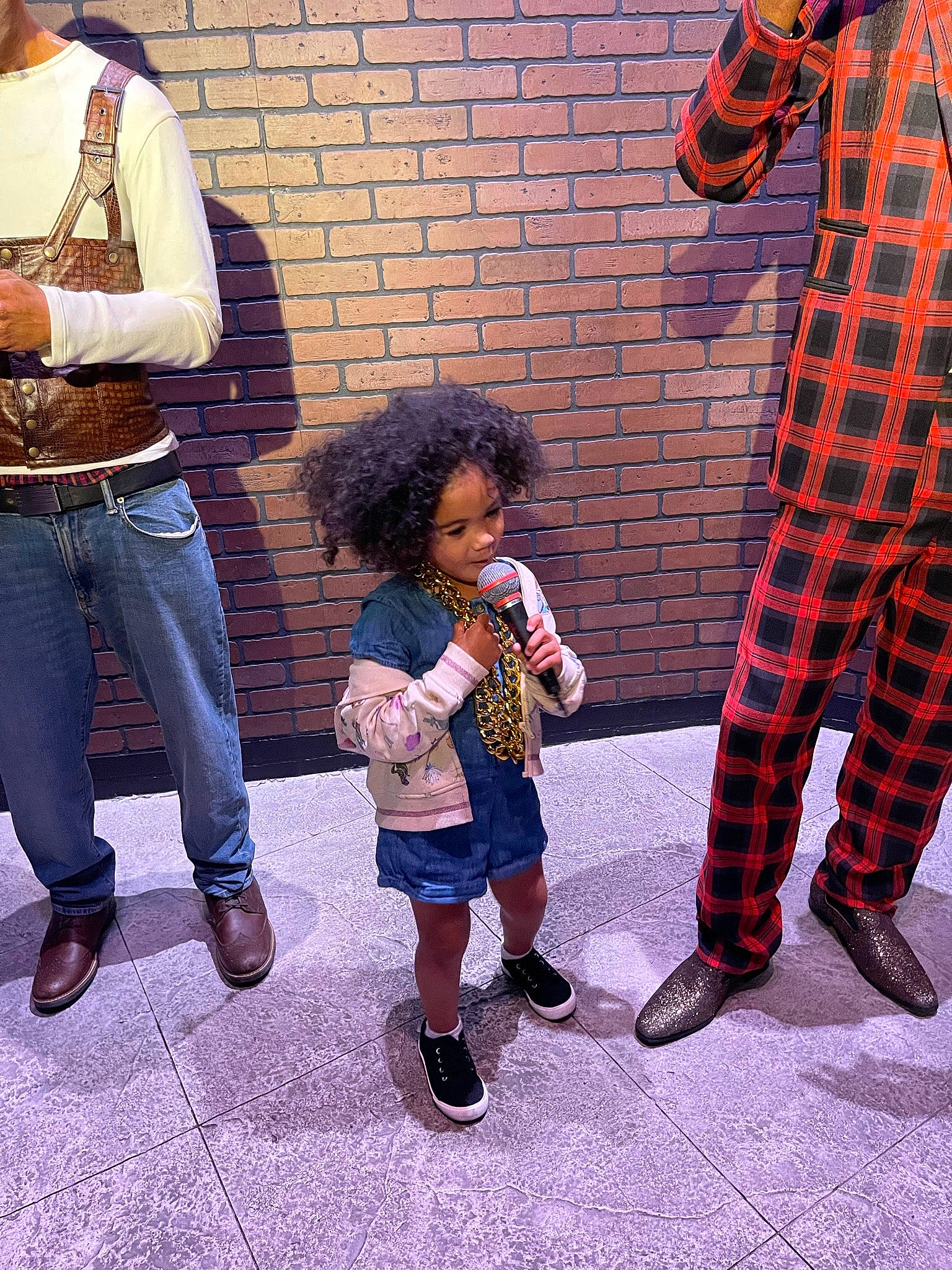 Tiana is registered to the contest to win money with this photo: bag, boot, child, cool, costume, event, flooring, footwear, fun, gesture, leg, luggage_and_bags, pedestrian, person, plaid, shoe, sidewalk, sneakers, street, tartan