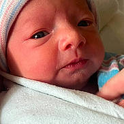 Celesté is registered to the contest to win money with this photo: baby, newborn, infant, swaddle, hospital_blanket, striped_hat, close_up, face, eyes, nose, lips, cheek, skin, hand, cozy, portrait, blanket, cap, sleepy, newborn_baby