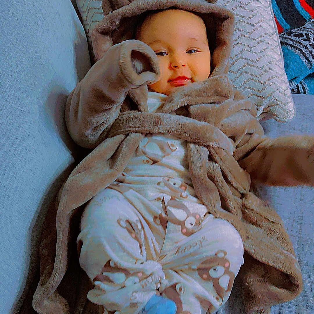 Sky-David joined the competition — help win amazing prizes! baby, bear_ears, blanket, blue_socks, child, couch, cozy, cute, face, home, indoors, infant, pajamas, person, pillow, relaxed, robe, seated, smiling, soft_fabric
