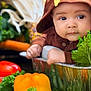 baby, child, hoodie, bunny_ears, vegetables, bell_pepper, carrot, lettuce, greenery, metal_container, cute, portrait, indoors, fresh, healthy, food, playful, face, expression, infant