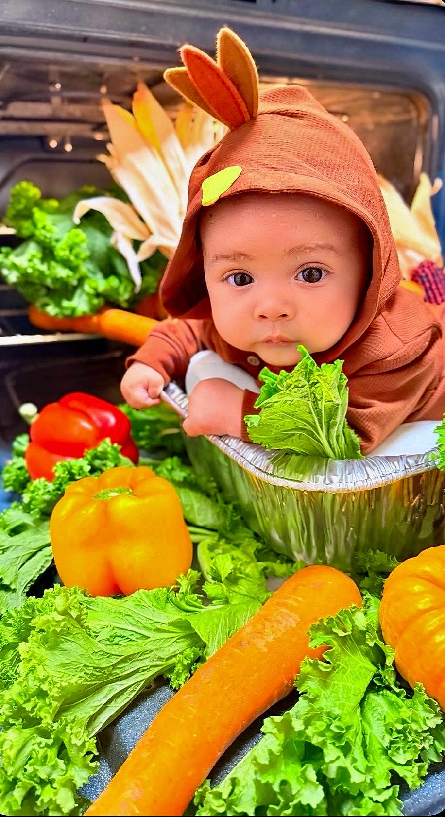 Mathias joined the competition — help win amazing prizes! baby, child, vegetables, lettuce, carrot, bell_pepper, orange, red, green, foil_container, hood, costume, cute, food, fresh, healthy, portrait, indoor, close_up, expression