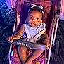 baby, barefoot, bow, carpet, child, clothing, curious, cute, footwear, headband, indoor, infant, person, purple, seatbelt, sitting, smiling, stroller, toddler, young_child