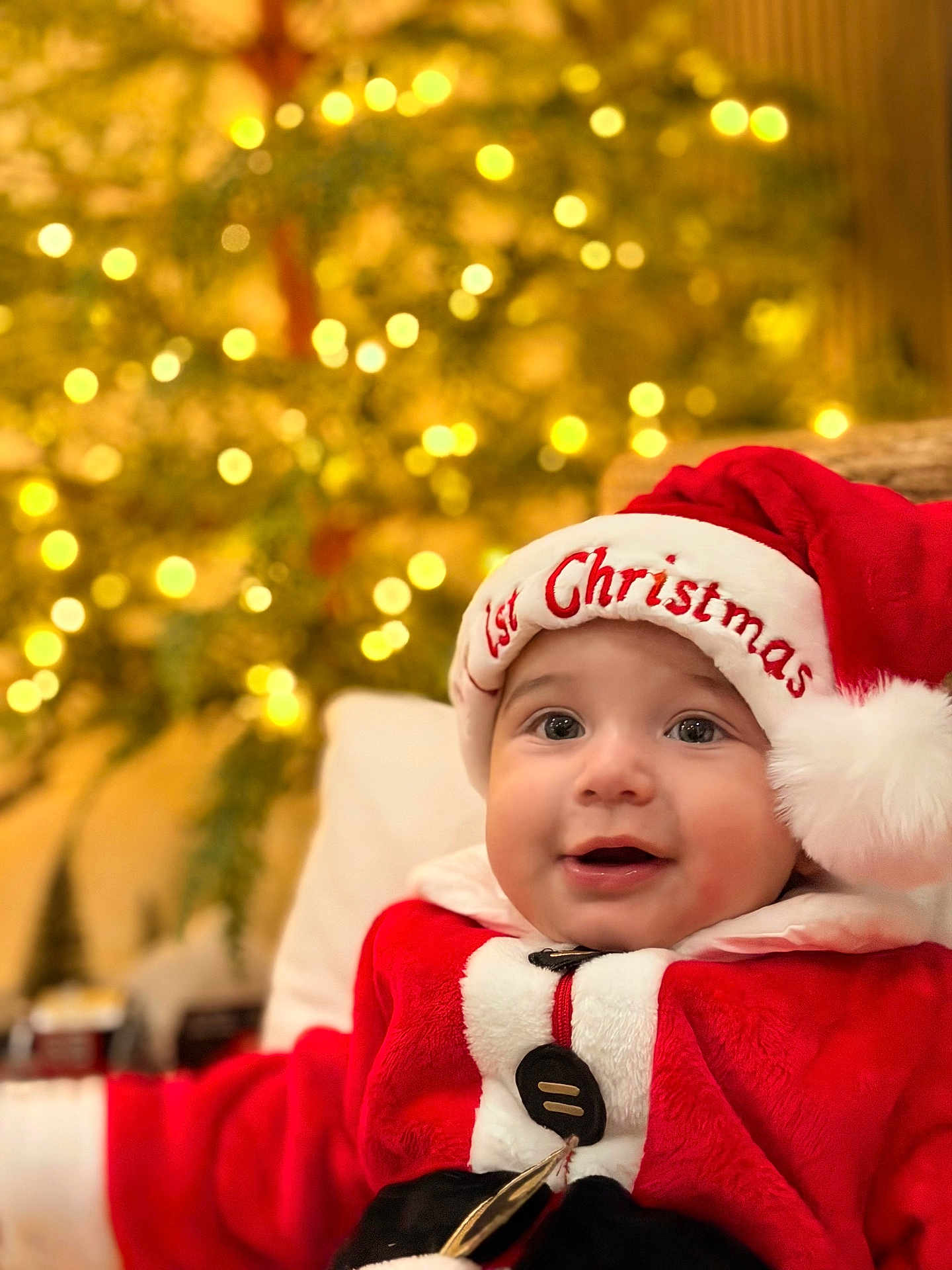 Lucca is registered to the contest to win money with this photo: baby, child, santa_hat, christmas, holiday, festive, smile, face, portrait, red_clothing, white_fur, button, indoor, lights, bokeh, celebration, cute, seasonal, happy, infant