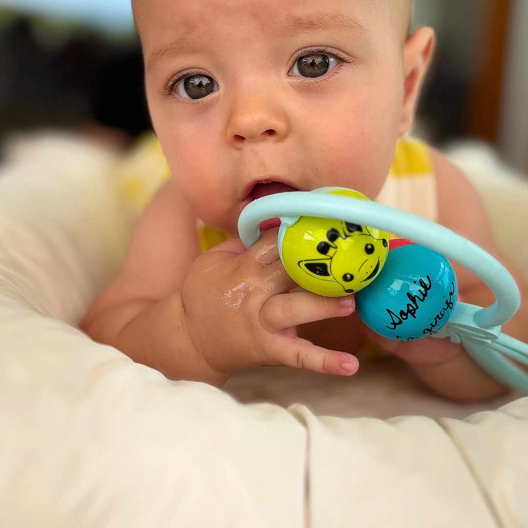Owen participe au concours pour gagner de l'argent avec cette photo : baby, chewing, child, closeup, comfort, curious, cushion, cute, expression, eyes, face, giraffe, hand, indoor, infant, person, skin, soft, toy, young