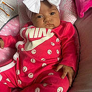 Zaniyah is registered to the contest to win money with this photo: baby, infant, pink_outfit, headband, white_bow, smiley_faces, baby_seat, cushion, plush_blanket, face, person, child, indoors, portrait, clothing, soft_toys, cute, relaxed, fashion, newborn