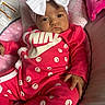 baby, infant, pink_outfit, headband, white_bow, smiley_faces, baby_seat, cushion, plush_blanket, face, person, child, indoors, portrait, clothing, soft_toys, cute, relaxed, fashion, newborn