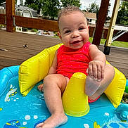 Delilah is registered to the contest to win money with this photo: baby, infant, smiling, sitting, inflatable_pool, water, red_swimsuit, playful, deck, outdoor, summer, foot, yellow_inflatable, child, happy, cute, sunny, blue, toy, toddler